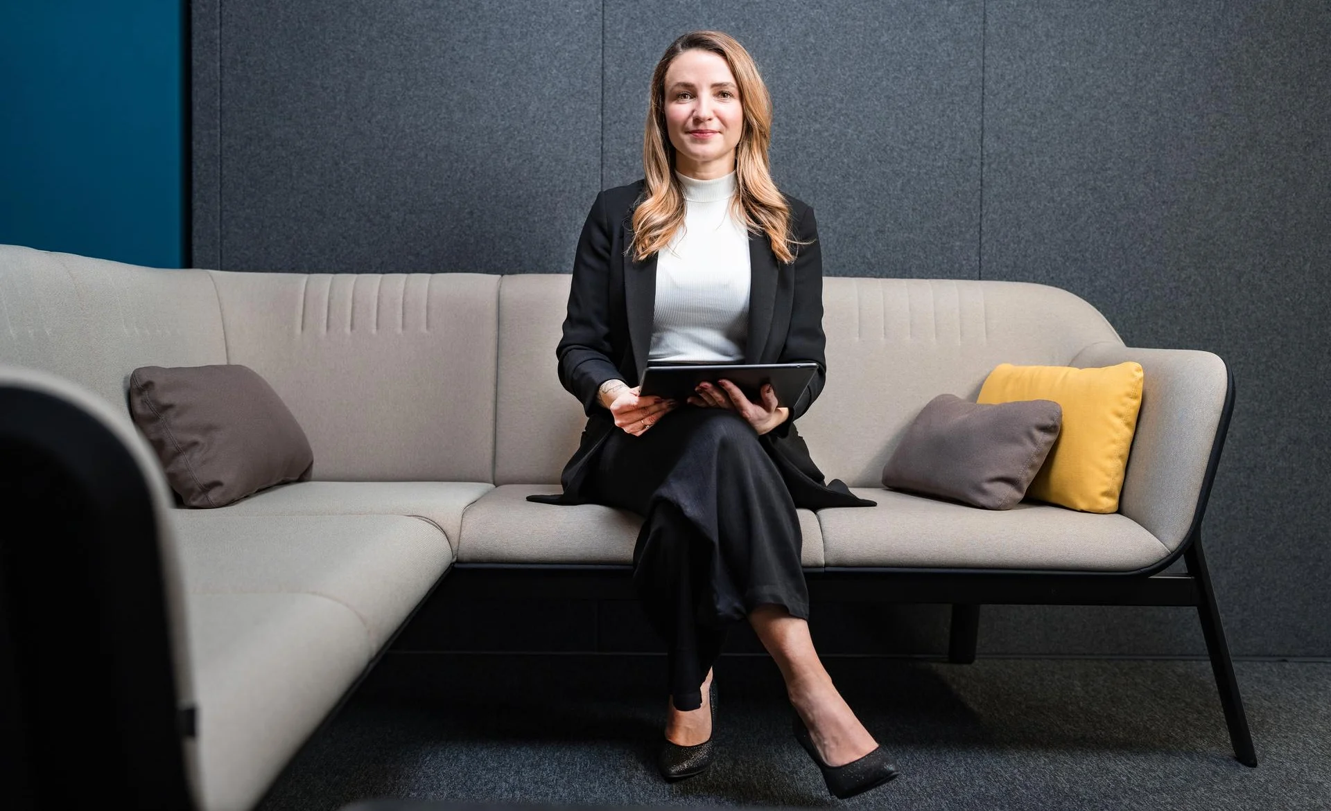 Frau sitzt auf Sofa mit Laptop in der Hand