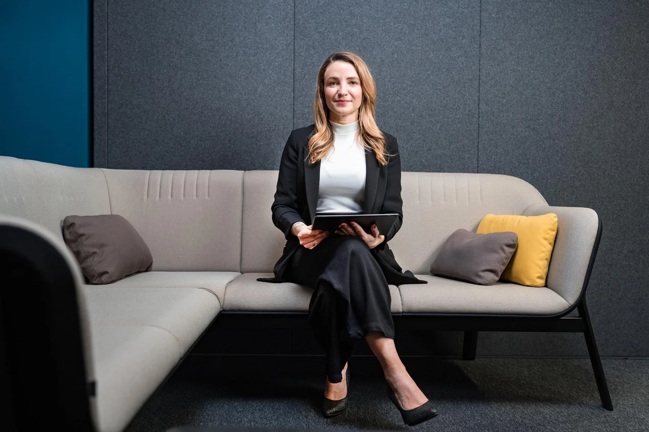 Frau sitzt auf Sofa mit Laptop in der Hand