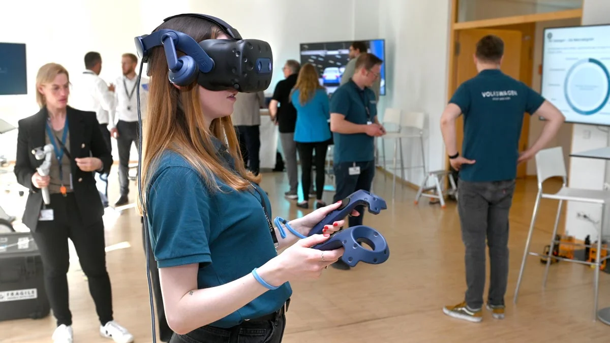Eine Frau mit Virtual-Reality-Headset erlebt praxisnahe Anwendungen während einer Live-Demonstration der Volkswagen Group Services.